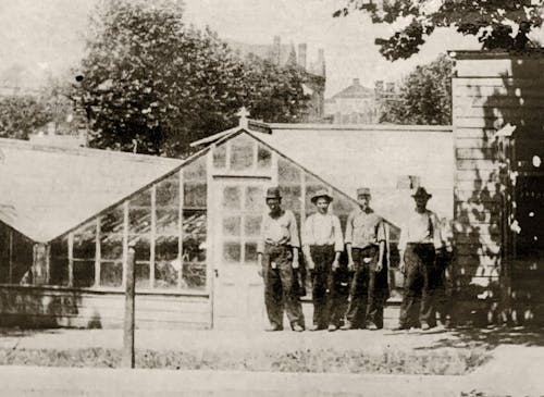 Four workers pose outside our original greenhouse in this undated 19th century photograph